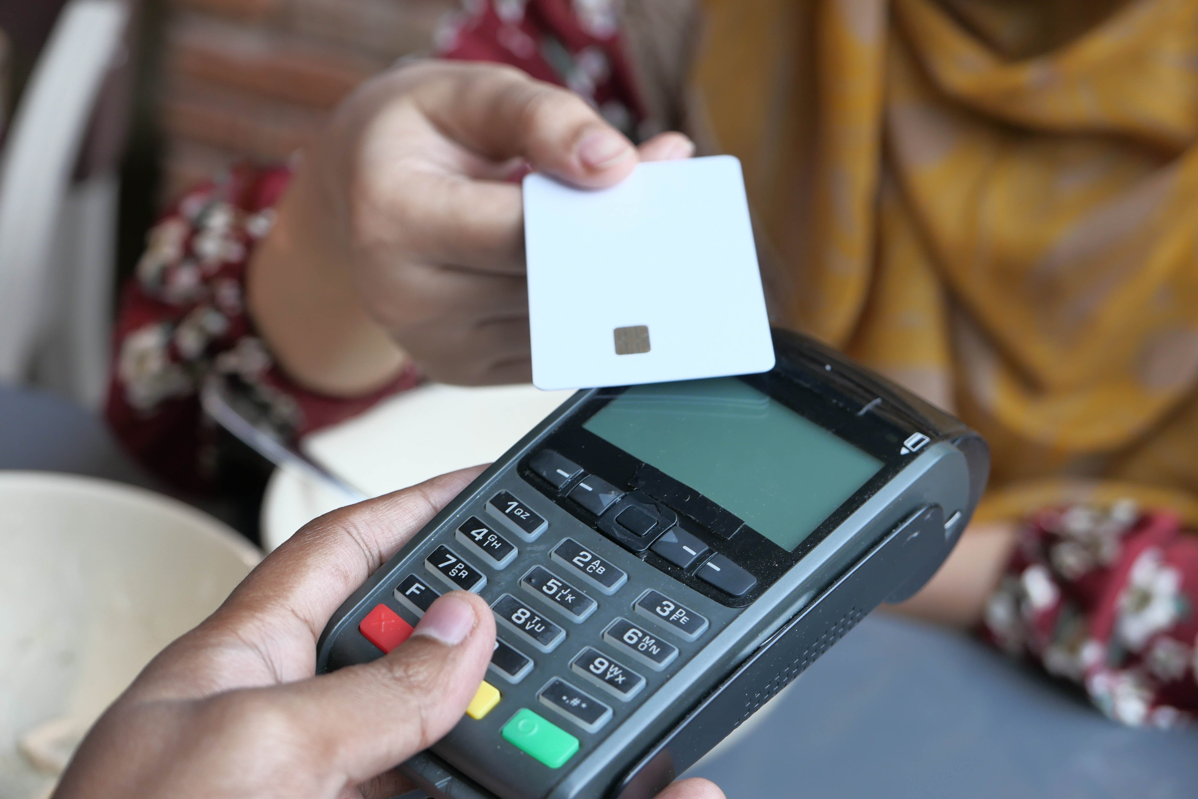 Woman tapping a credit card on a point of sale machine.
